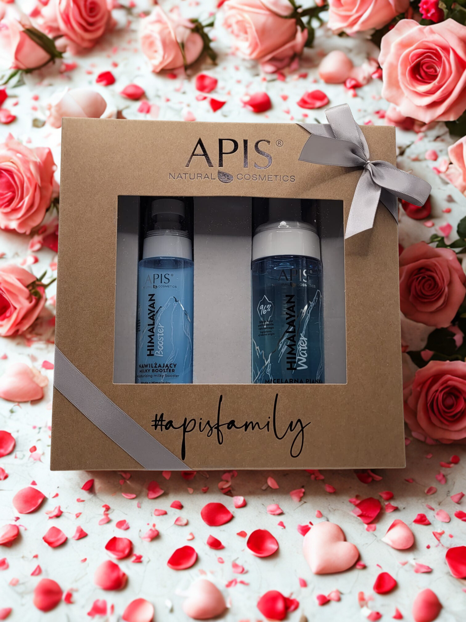 APIS cosmetic set with bottles in a decorative box surrounded by pink roses and petals.