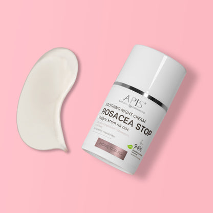 A white cylindrical cosmetic bottle labeled APIS Soothing Night Cream Rosacea Stop, shown on a soft pink background with a curved smear of white cream beside it.